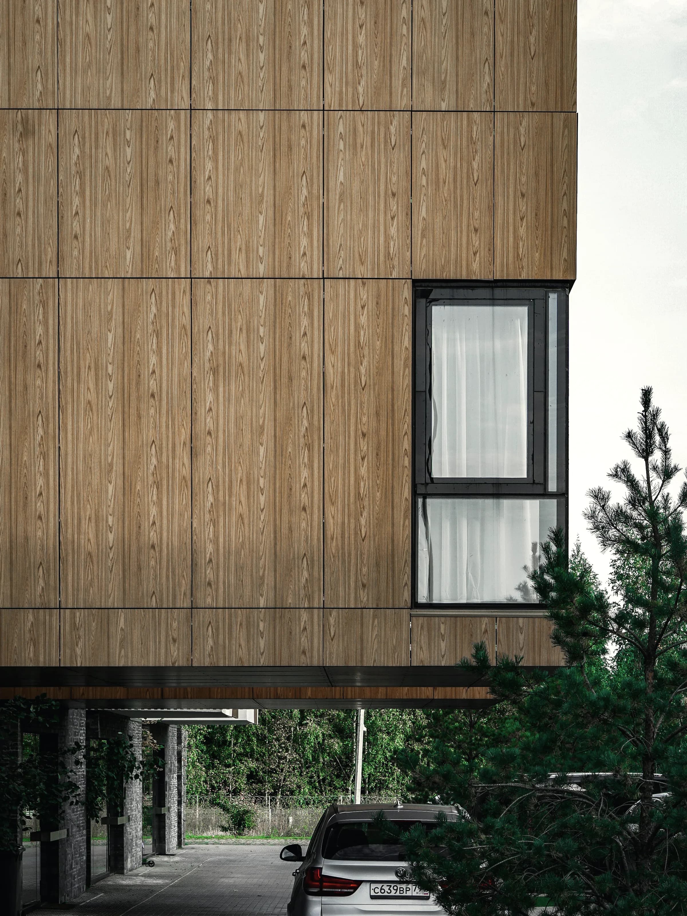 A timber soffit meeting frameless glazing, the structure carried past the line of the wall.