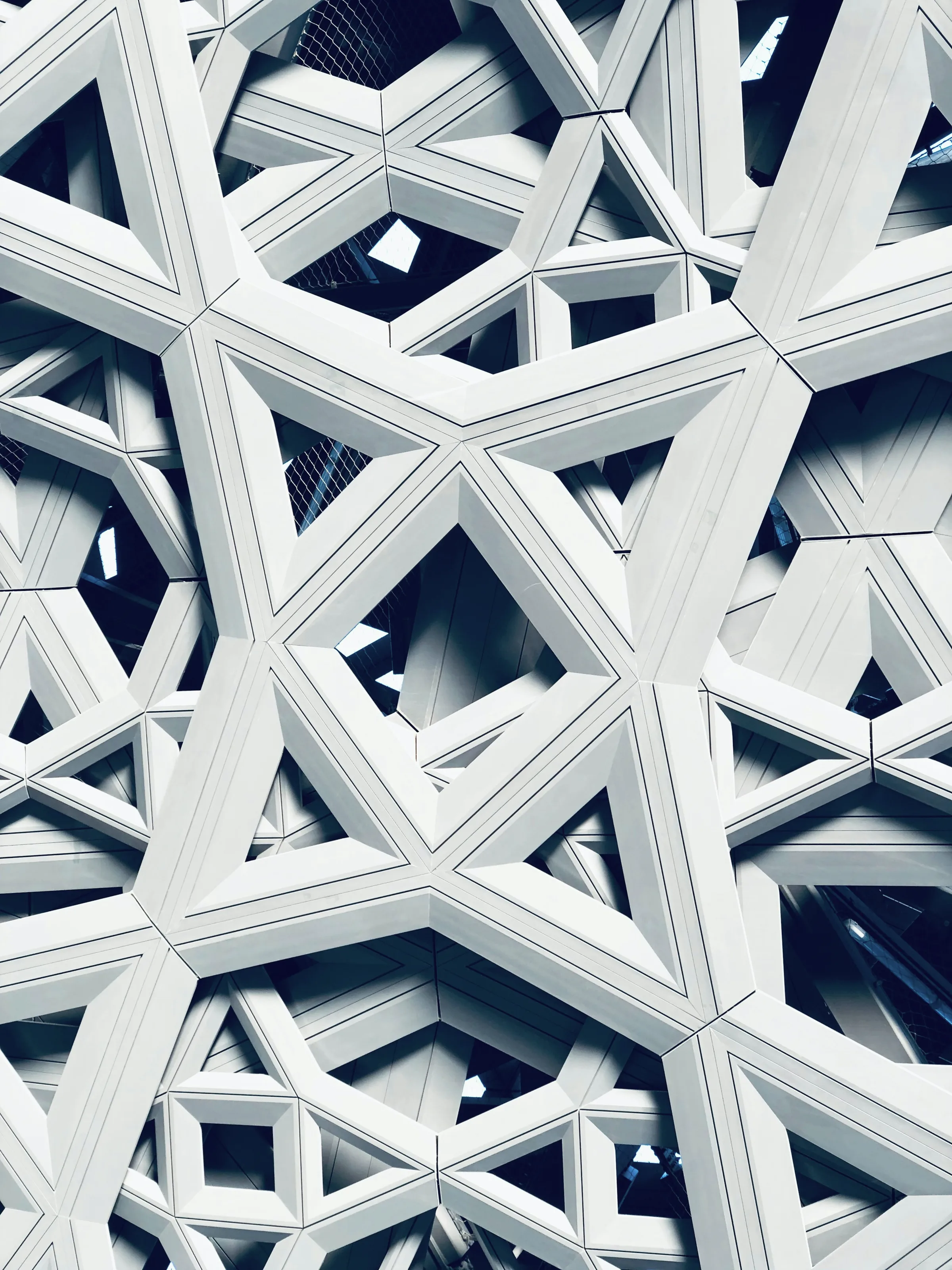A perforated canopy abstracted to pattern, daylight breaking through in points.