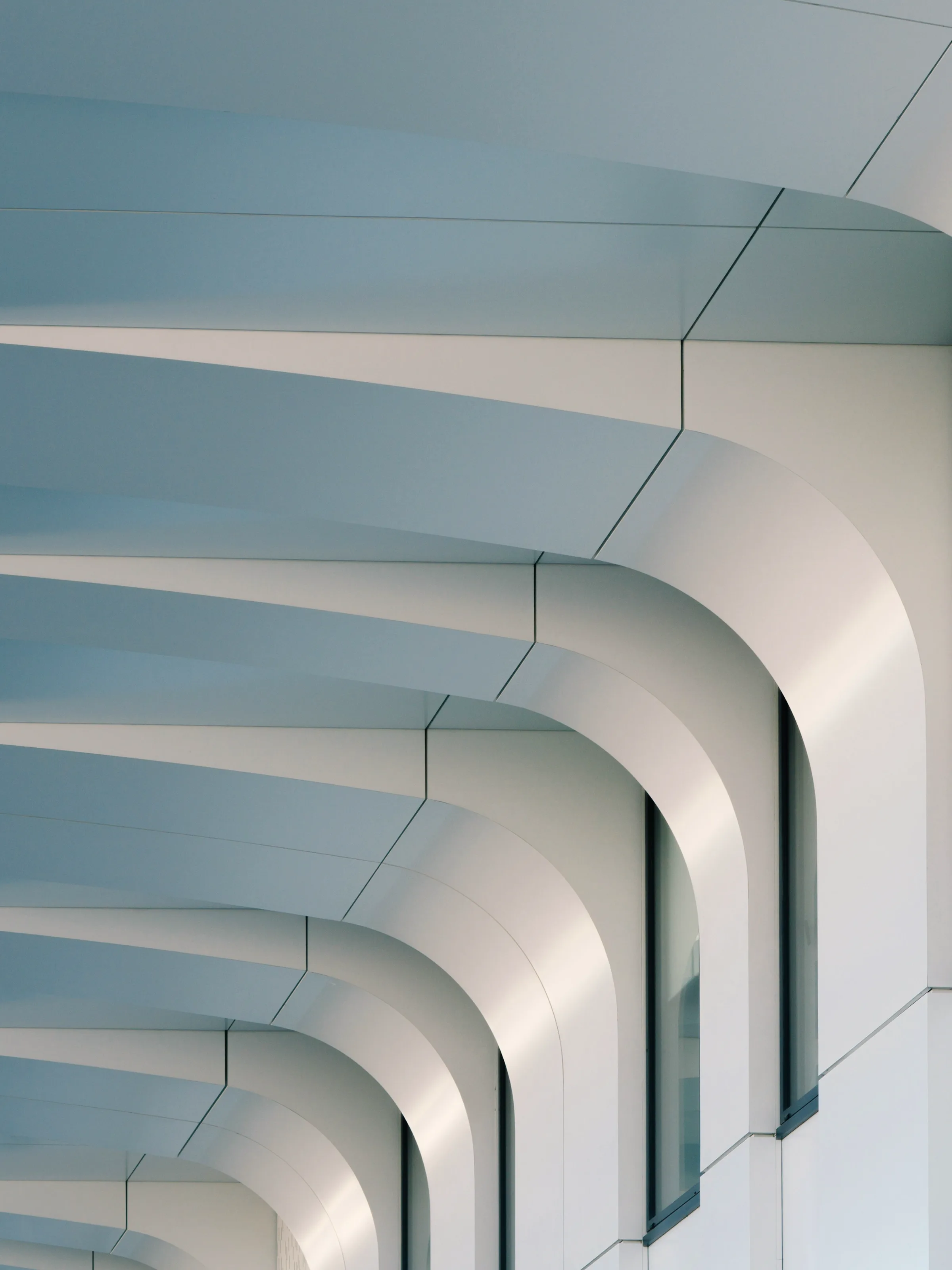 A metal facade detail, its fins set at a constant angle across the run.
