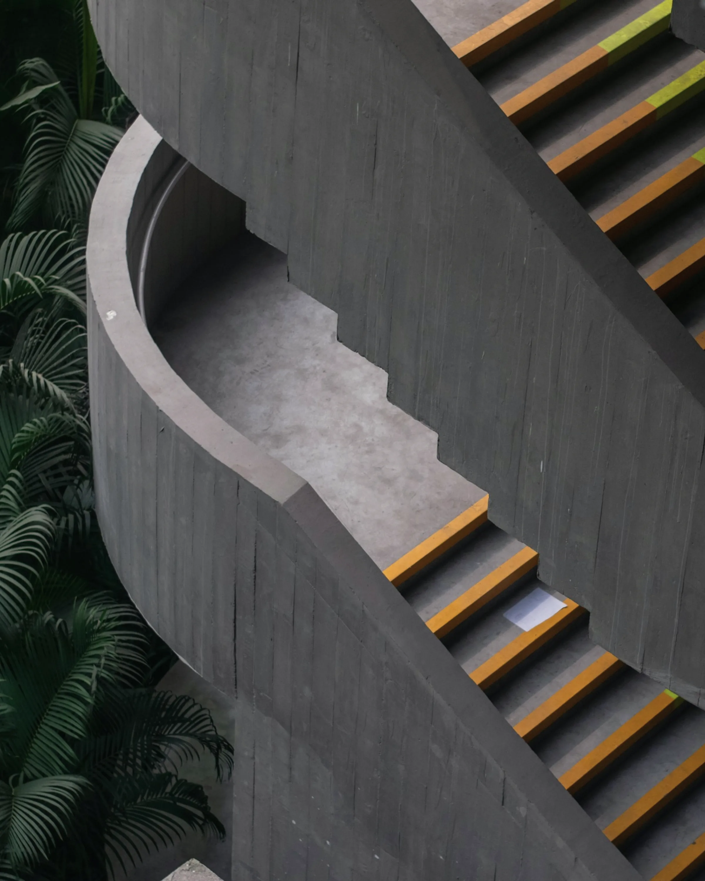 A concrete spiral stair seen from below, the soffit turning in one continuous surface.