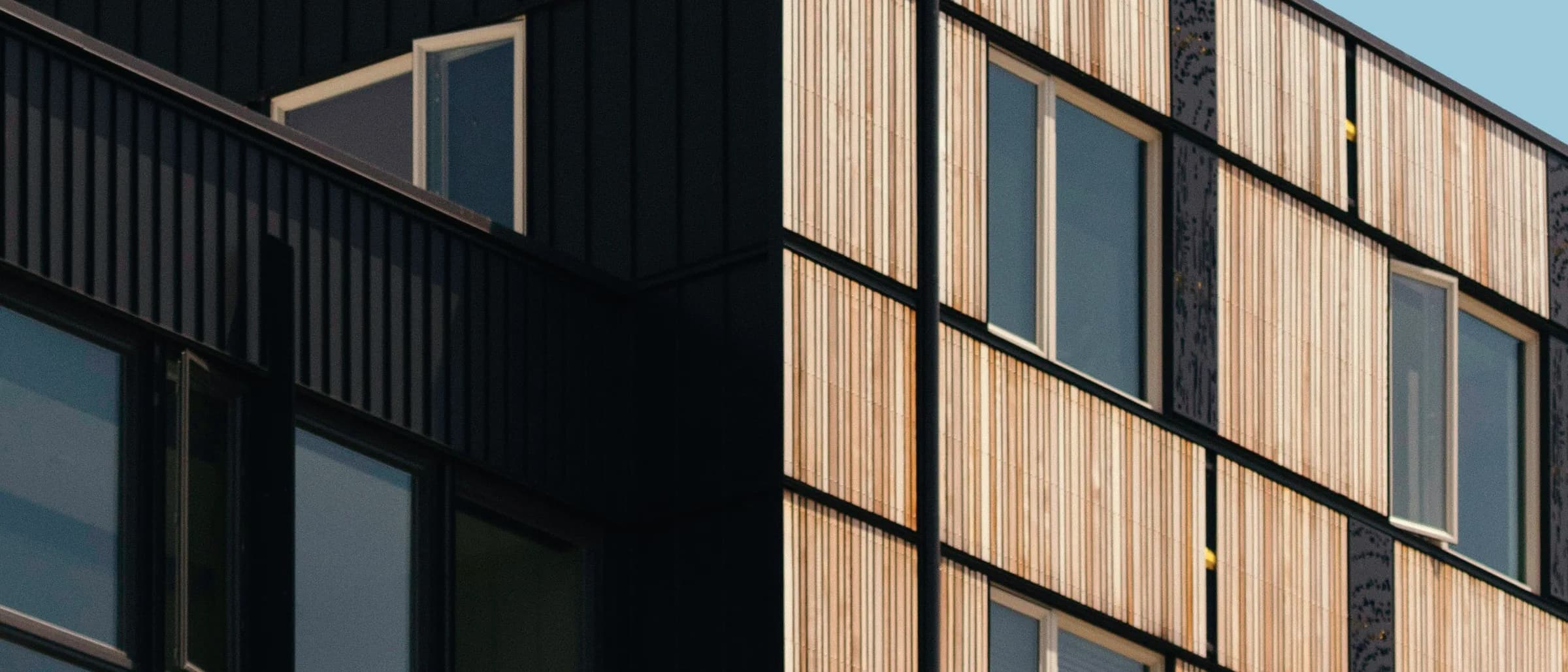 A residential block in dark and pale concrete, its balconies recessed into the facade.