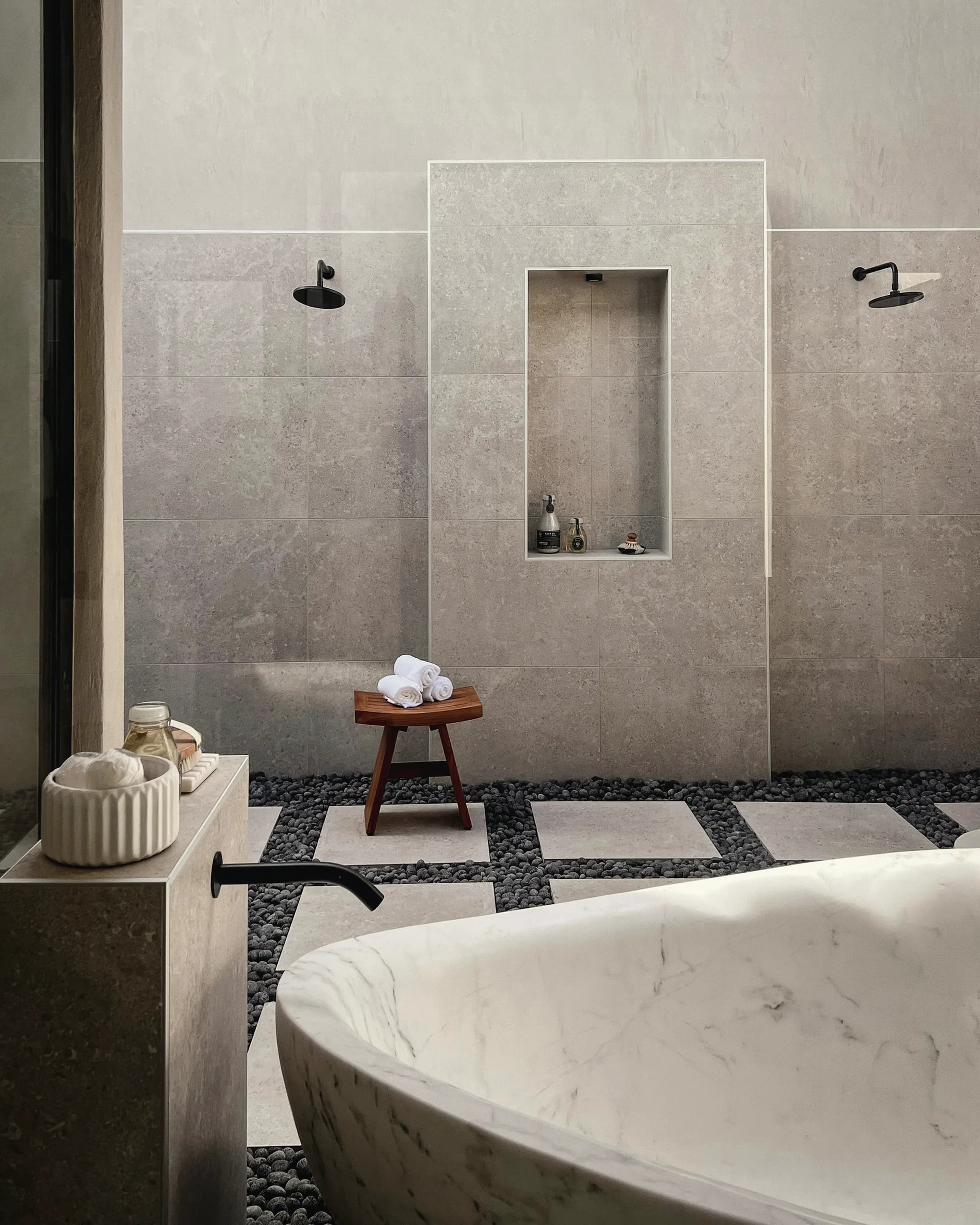 A bathroom lined in dark stone, lit from a single concealed source above the basin.