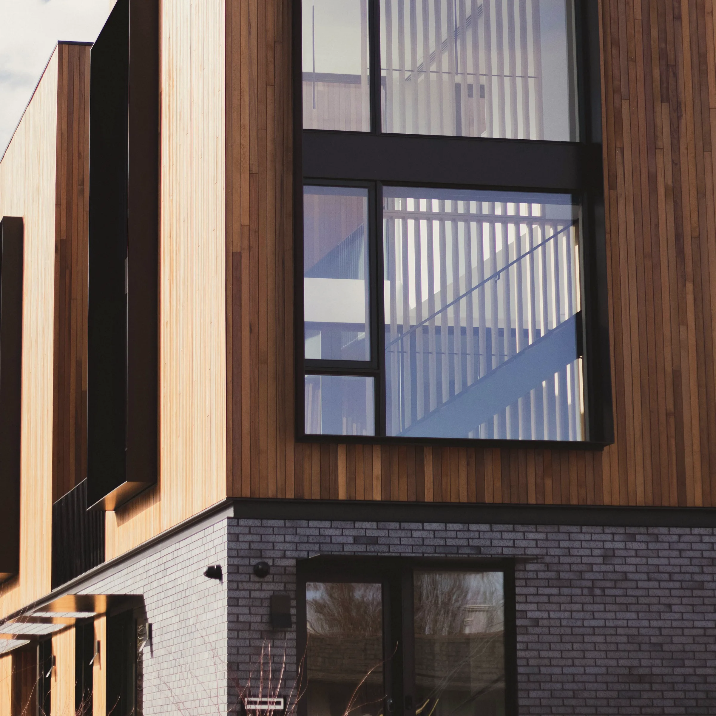 A timber-framed window set deep into its reveal, the frame detailed to sit flush.