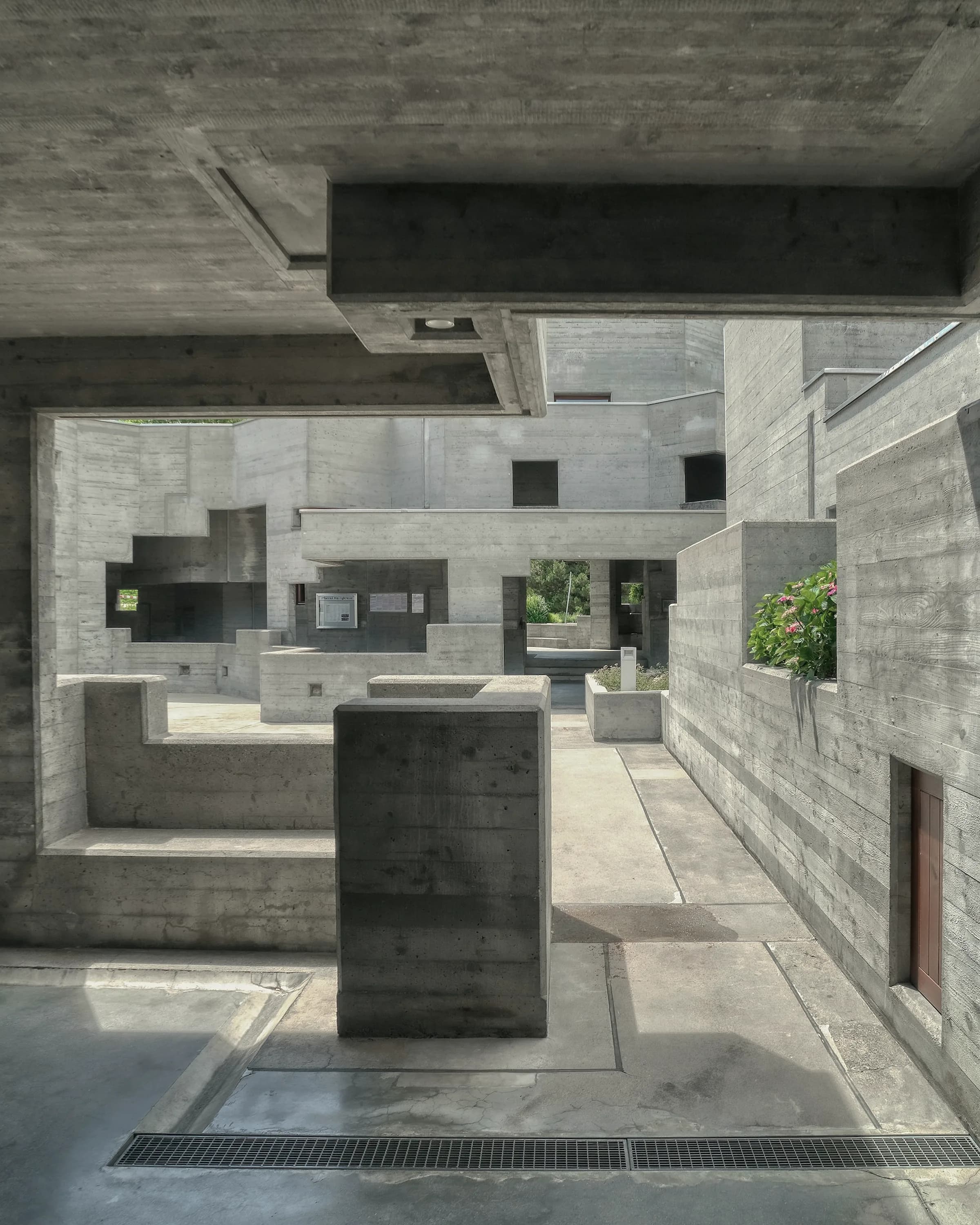 A concrete complex of stacked volumes stepping across the site.