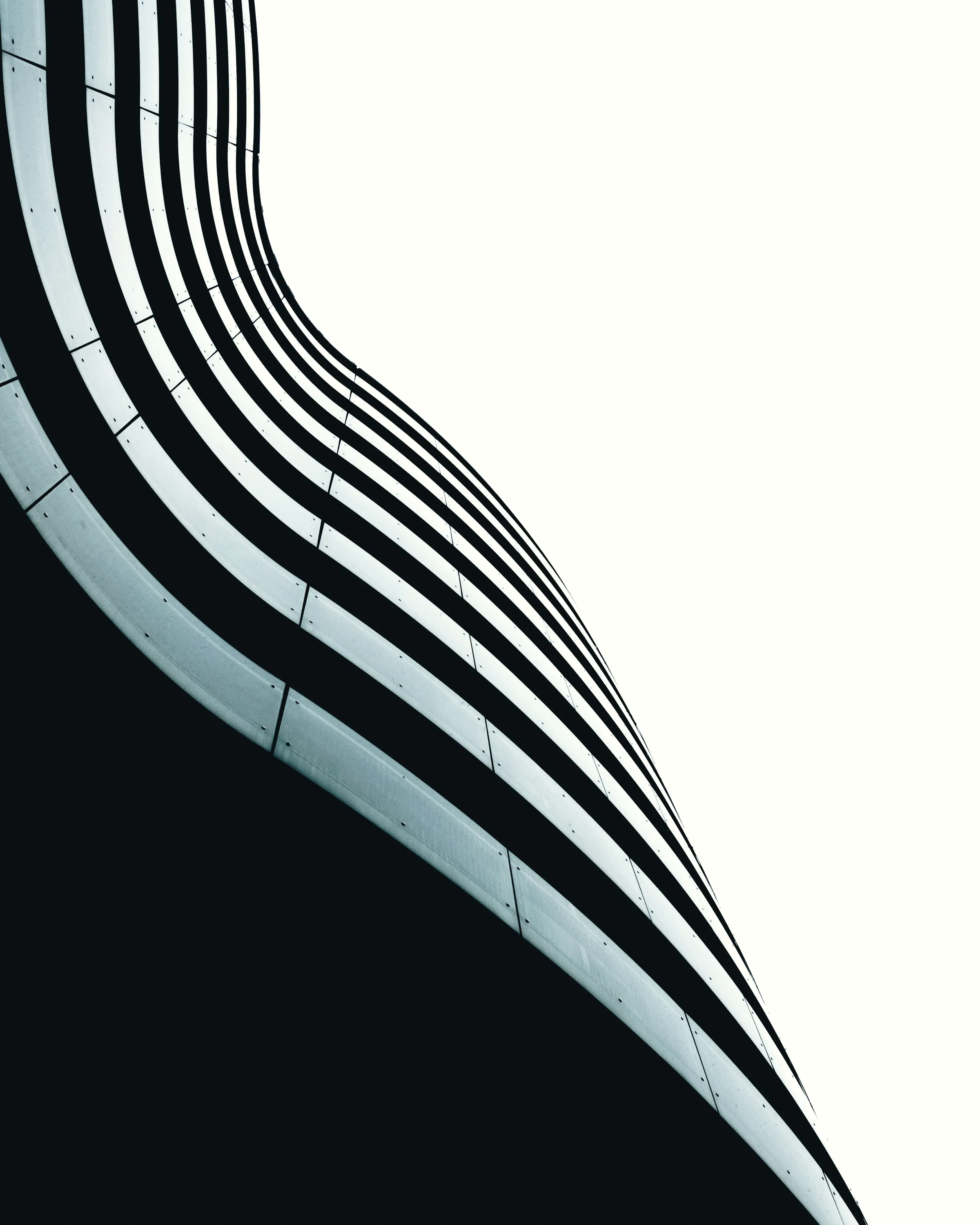 A curved facade of pale banding, turning away from the viewer.