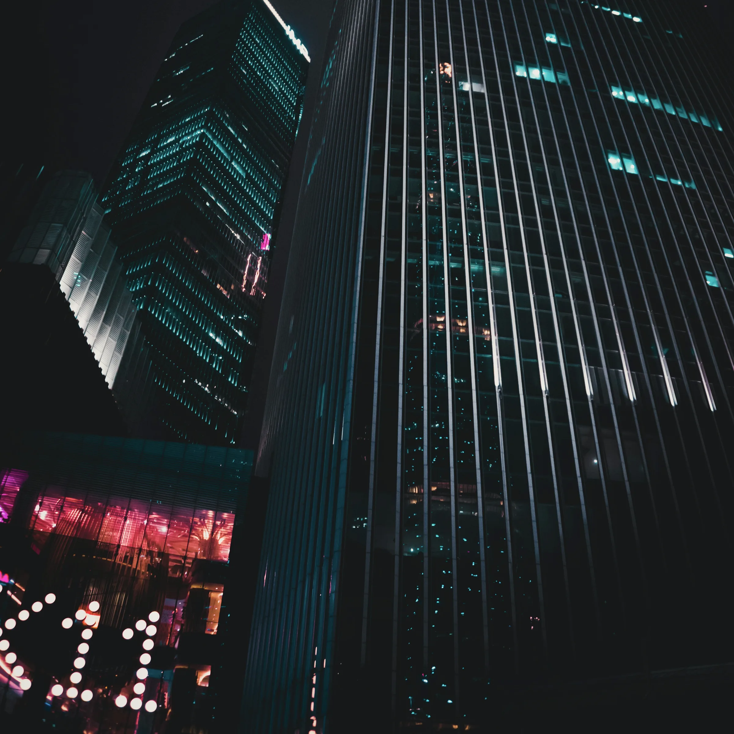 A dark high-rise seen from the pavement, the elevation converging toward the sky.