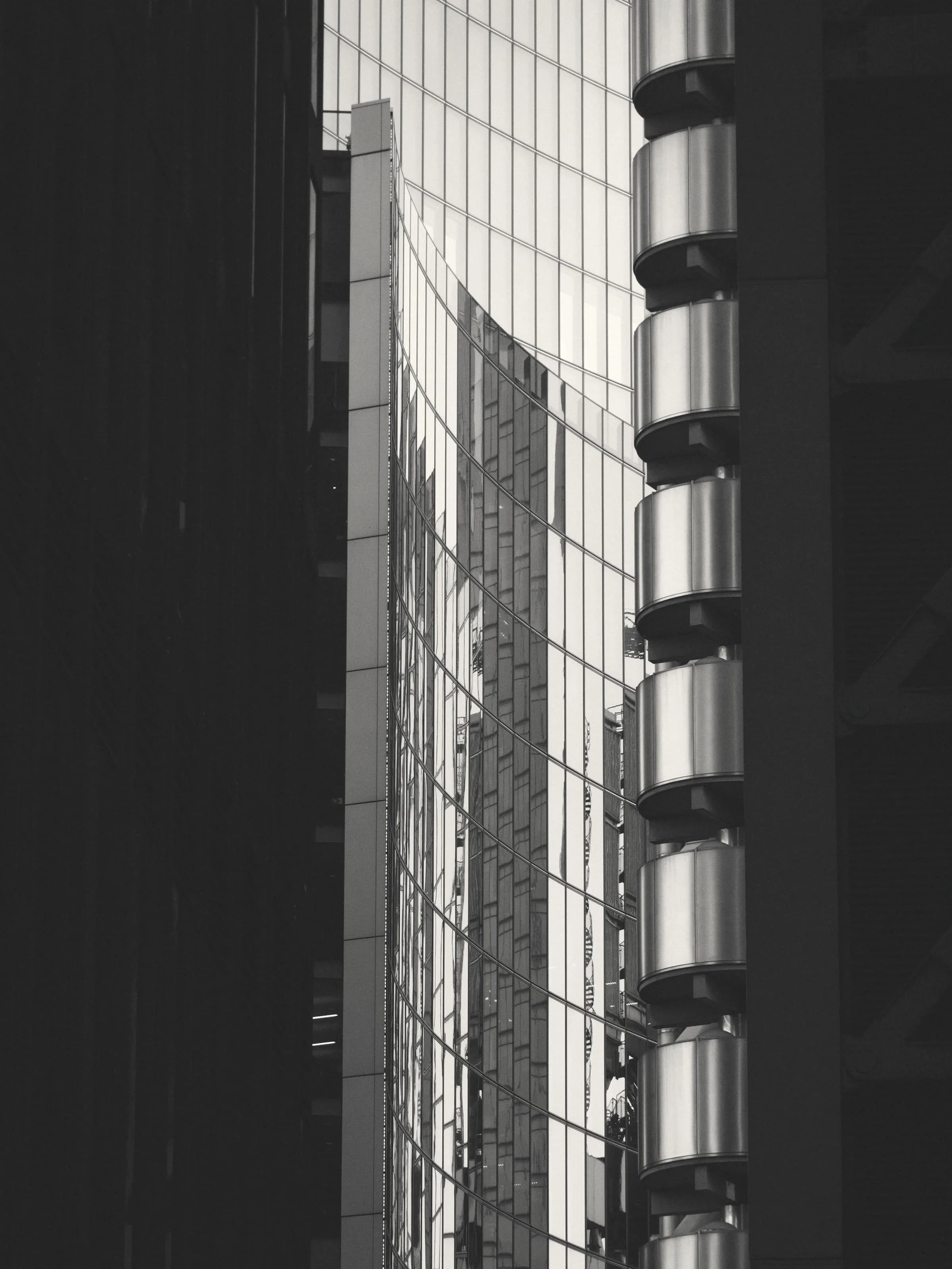 Two office towers standing close together, the gap between them cut hard by shadow.