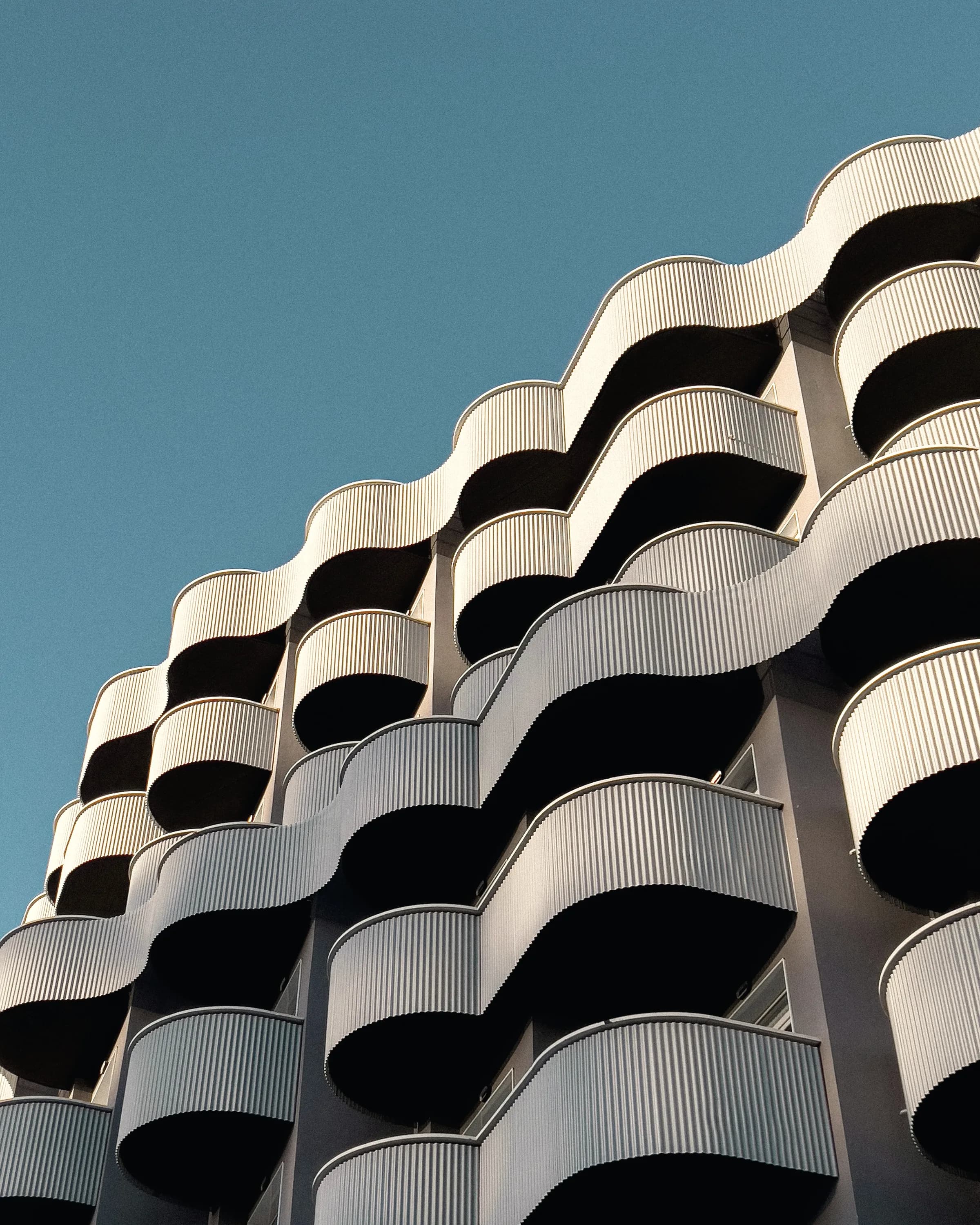 Curved balconies stacking up a residential elevation in a continuous run.