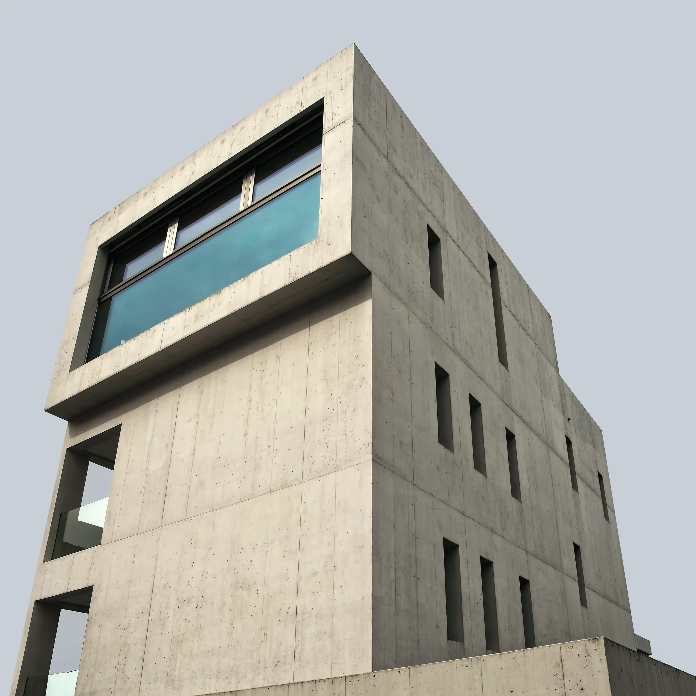 Cast concrete meeting glazing, the pour lines left legible across the face.
