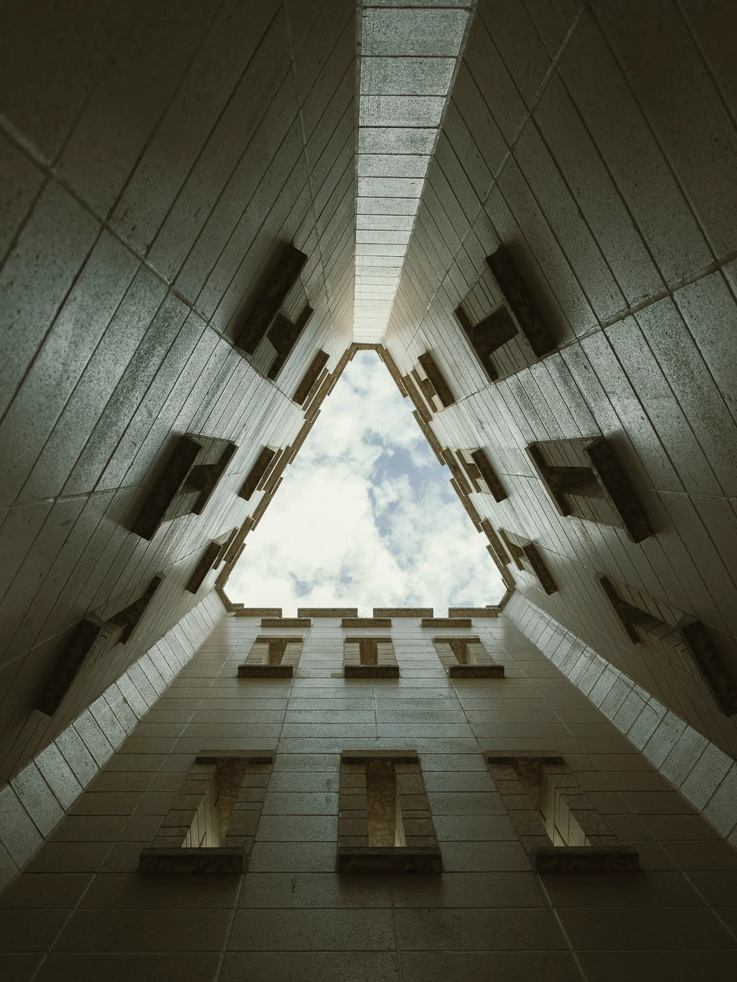 A triangular light shaft seen from the base, opening to cloud far above.